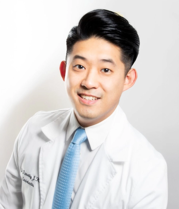 Endodontist Timothy Kim Smiling In Lab Coat In Front Of White Background