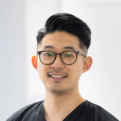 Endodontist Timothy Kim Smiling In Black Scrubs And Glasses